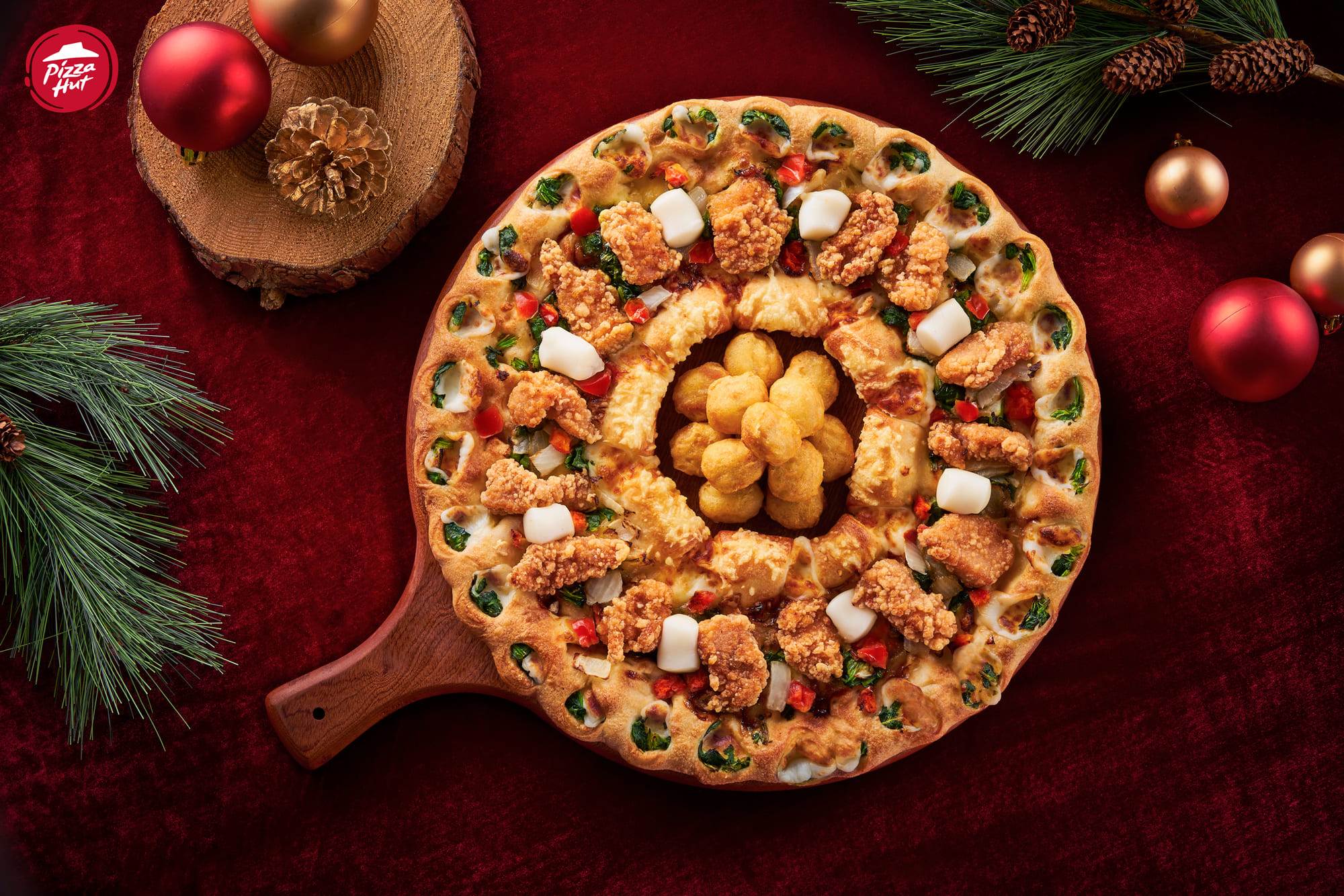 圖一：必勝客「聖誕花圈黃金雞比薩」鋪滿先炸後烤的燦金香酥雞與番茄點綴，搭配內外雙圈芝心餅皮並嵌入菠菜，交織出金、紅、綠的聖誕經典色彩